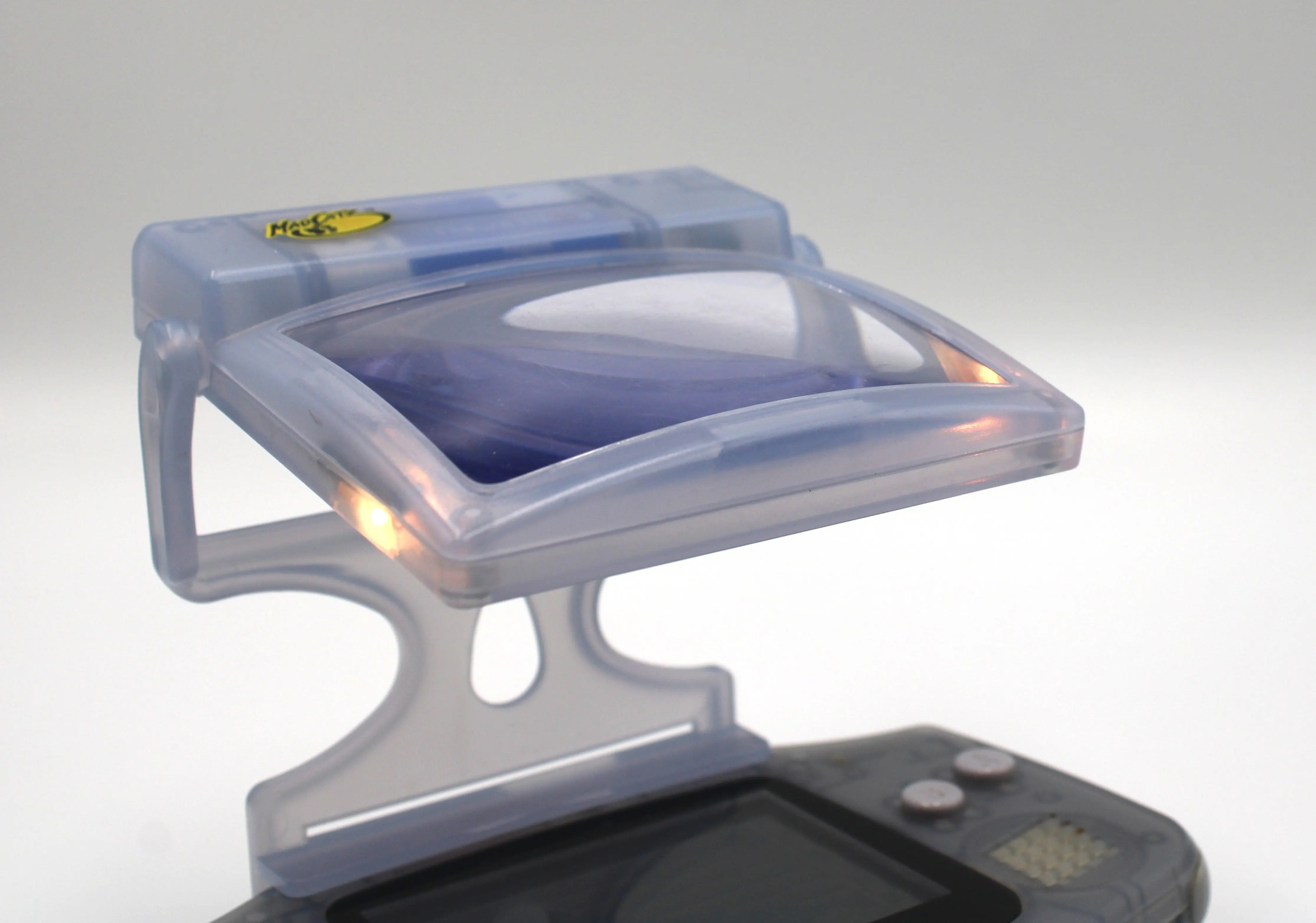 Pre-owned NTSC-U Glacier Ice Blue Nintendo Game Boy Advance (GBA) Mad Catz Light & Screen Magnifier. Picture of attached to GBA lit up.