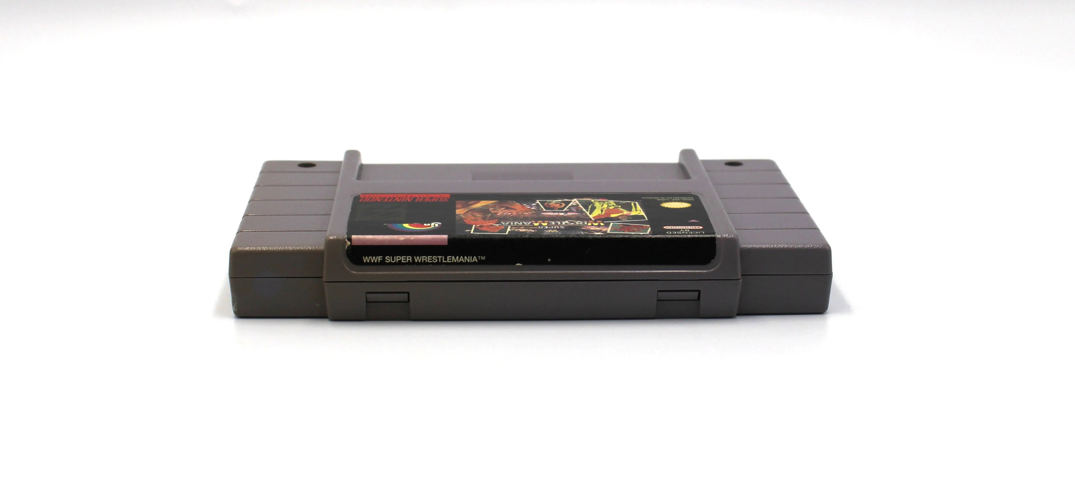 Top cartridge view of retro SNES game WWF Super WrestleMania. See picture of top label of the NTSC-U cartridge with minor wear from age and use.
