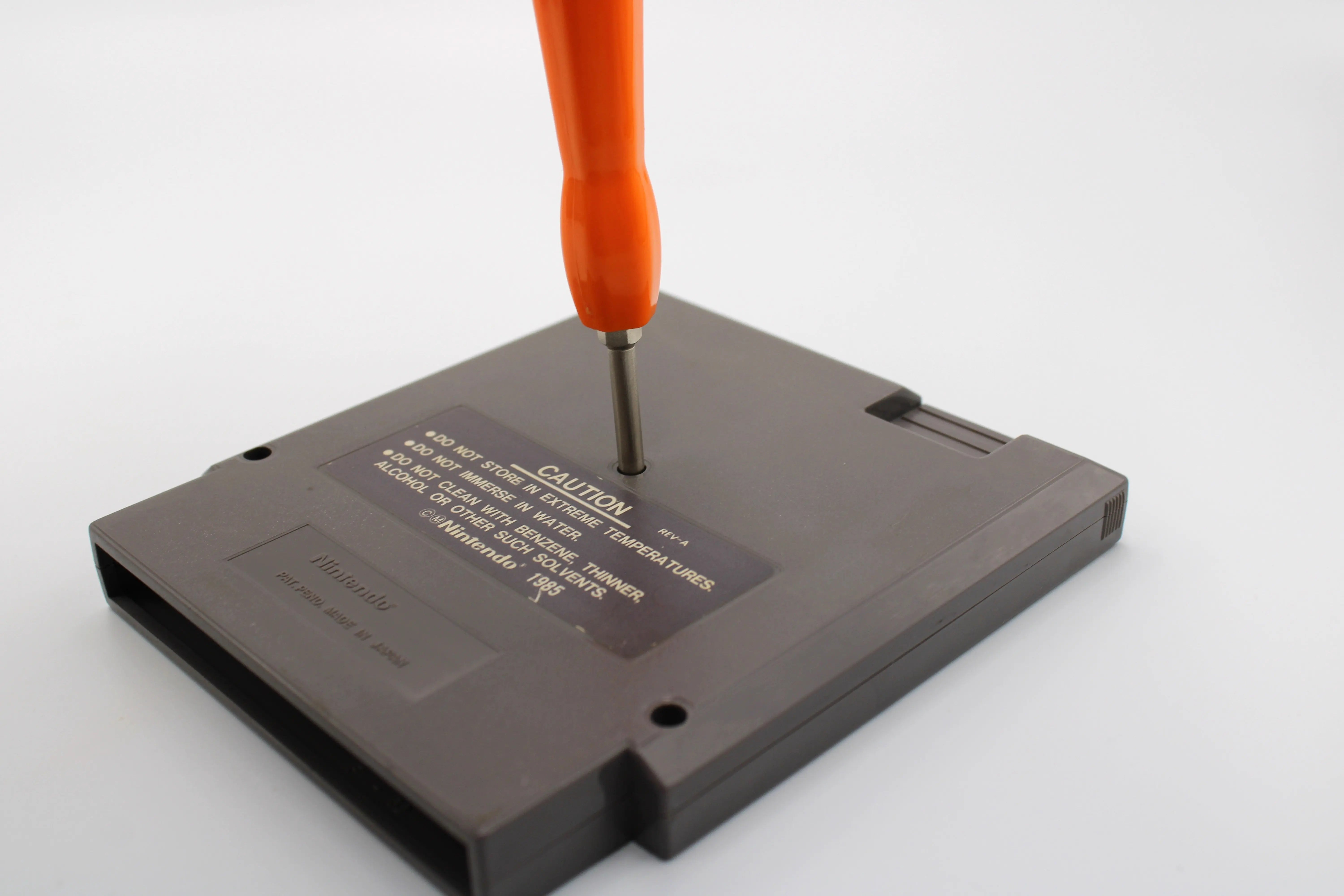 View of 4.5mm & 3.8mm Nintendo Sega Gamebit Tool Orange Dual Set, Removable, Combo. View of the 3.8mm gamebit head in reference to using it for an NTSC-U NES game cartridge.