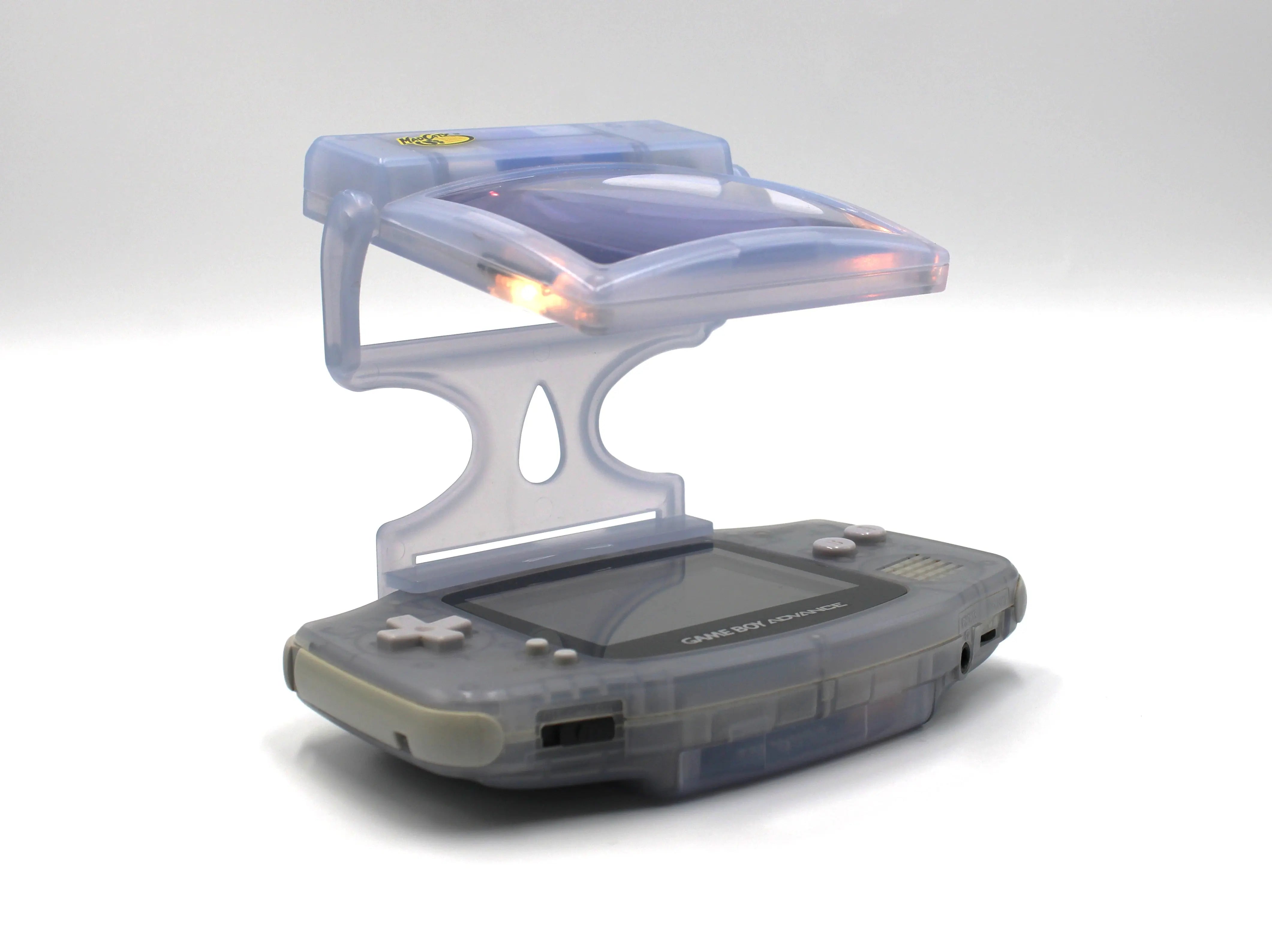 Pre-owned Glacier Ice Nintendo Game Boy Advance (GBA) Mad Catz Light & Screen Magnifier. Picture of gba with mad catz lit up magnifier at an angle.