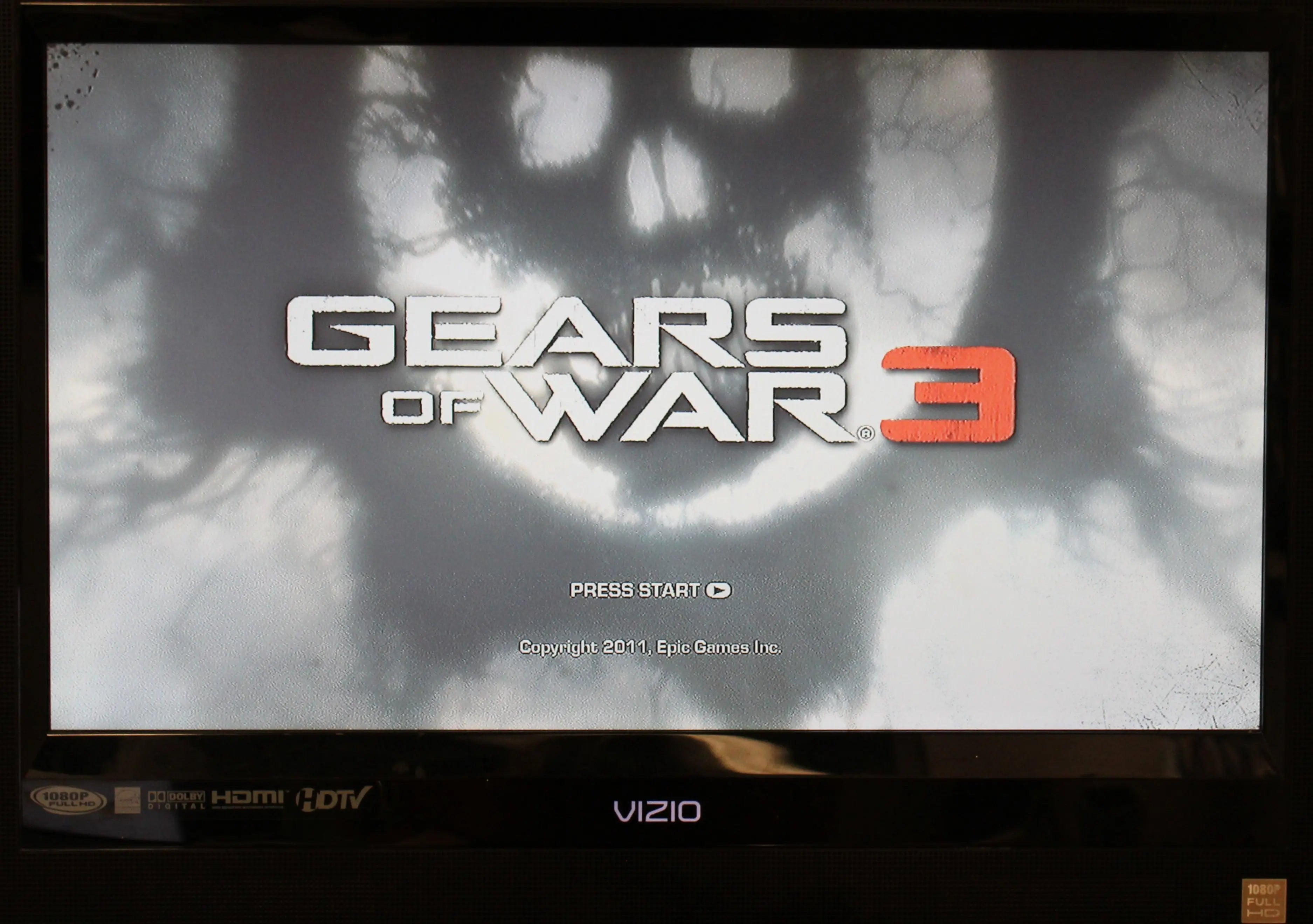 Gameplay screenshot of Gears of War 3 for Microsoft Xbox 360 NTSC-U, showing in-game shooter action and visual style main menu with options image.