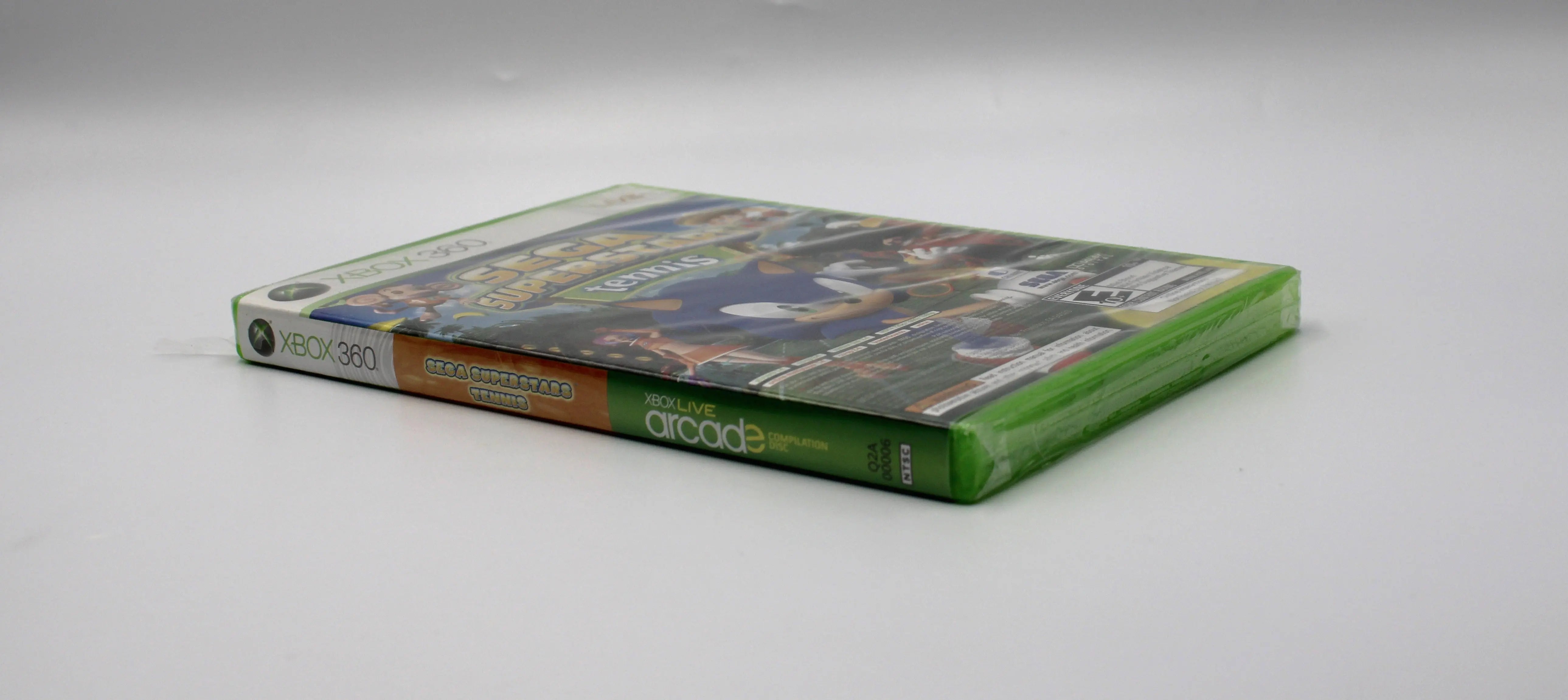 Angled game pine view of Sega Superstars Tennis & Arcade Compilation for Microsoft Xbox 360 NTSC-U sealed game case, showing titles text and sealed packaging.