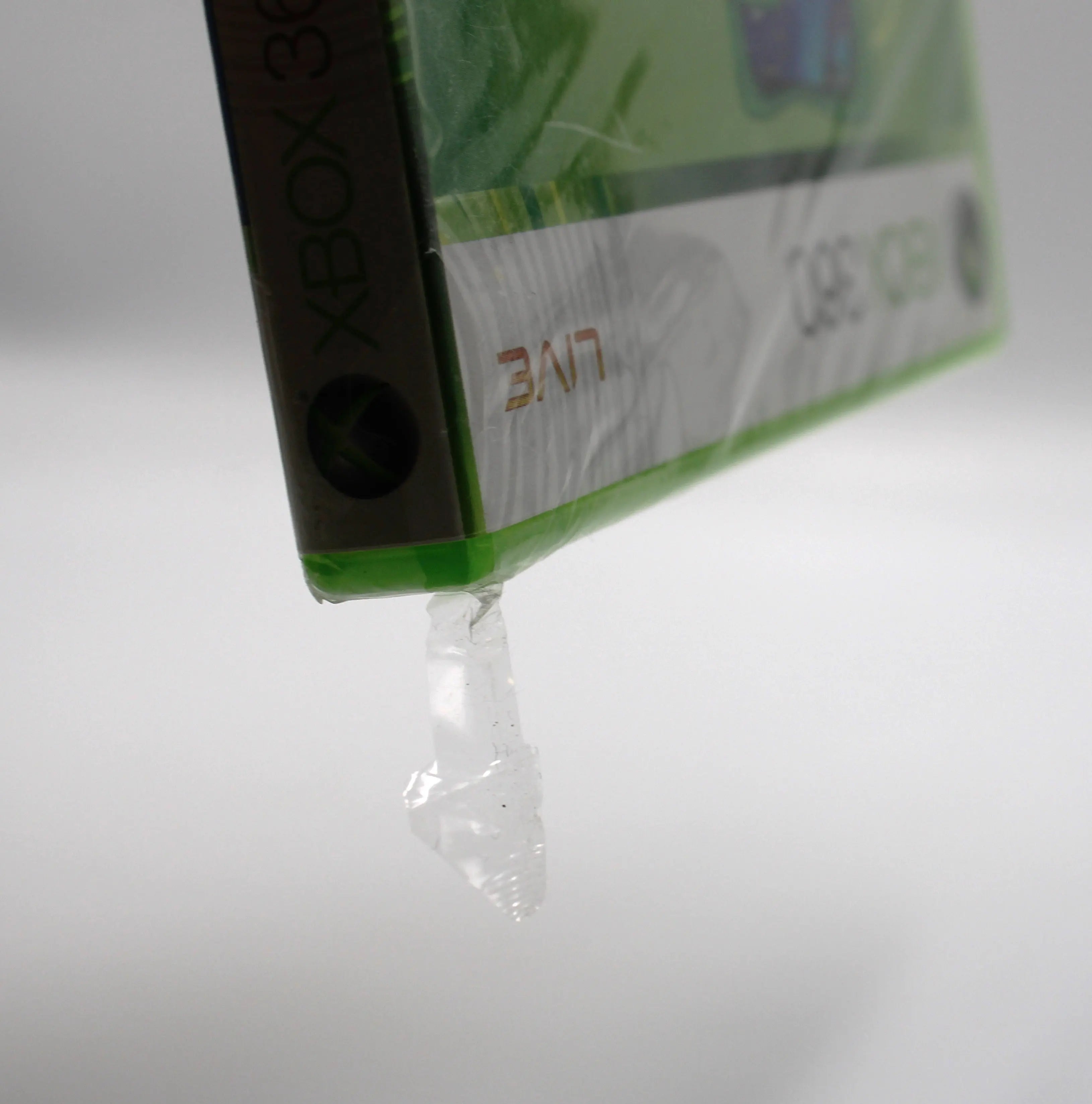 Close up view of Sega Superstars Tennis & Arcade Compilation for Microsoft Xbox 360 NTSC-U sealed game case, showing tear to top corner from different angle.