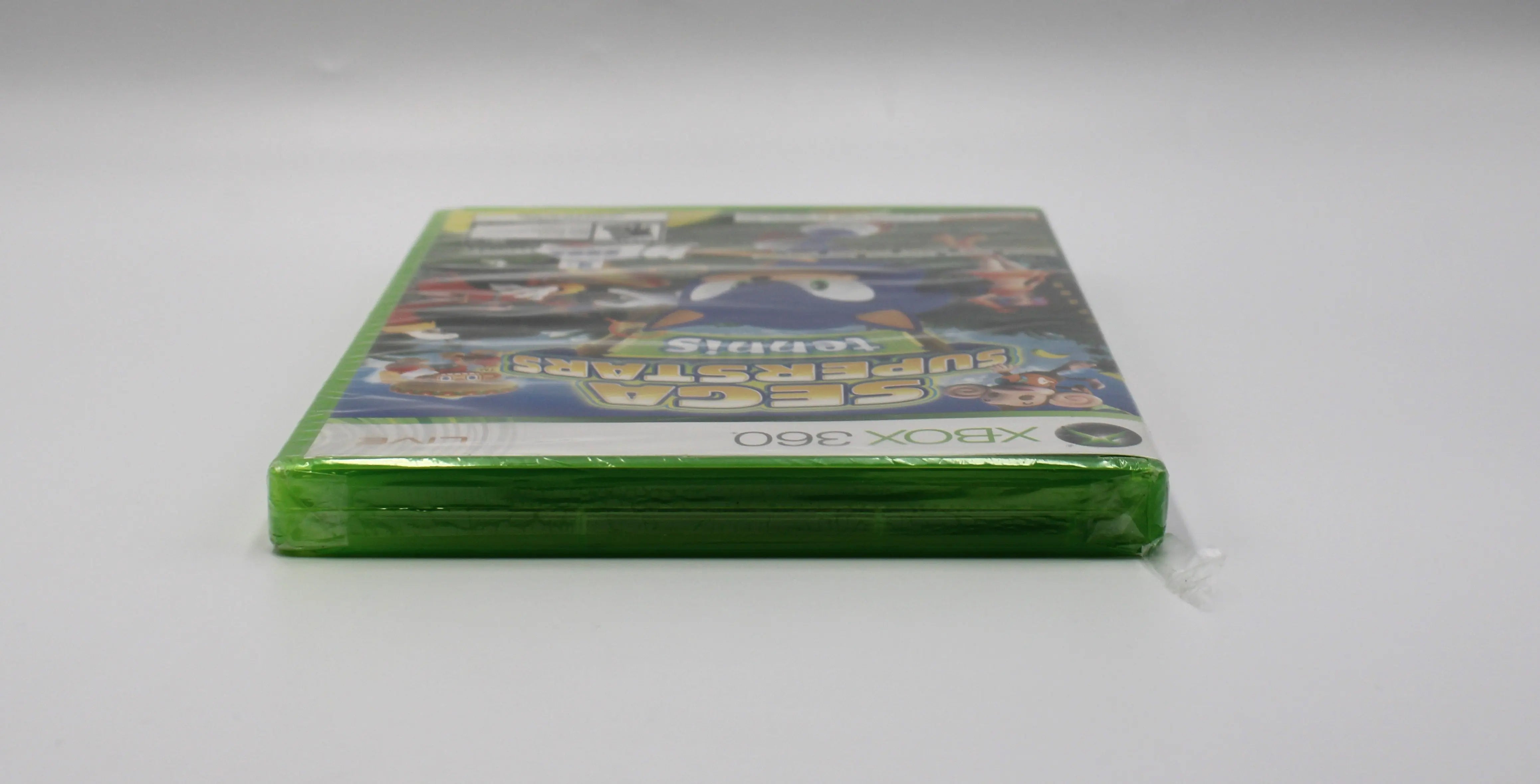 Top view of Sega Superstars Tennis & Arcade Compilation for Microsoft Xbox 360 NTSC-U sealed game case, showing sealed edges and plastic wrap condition with tear.