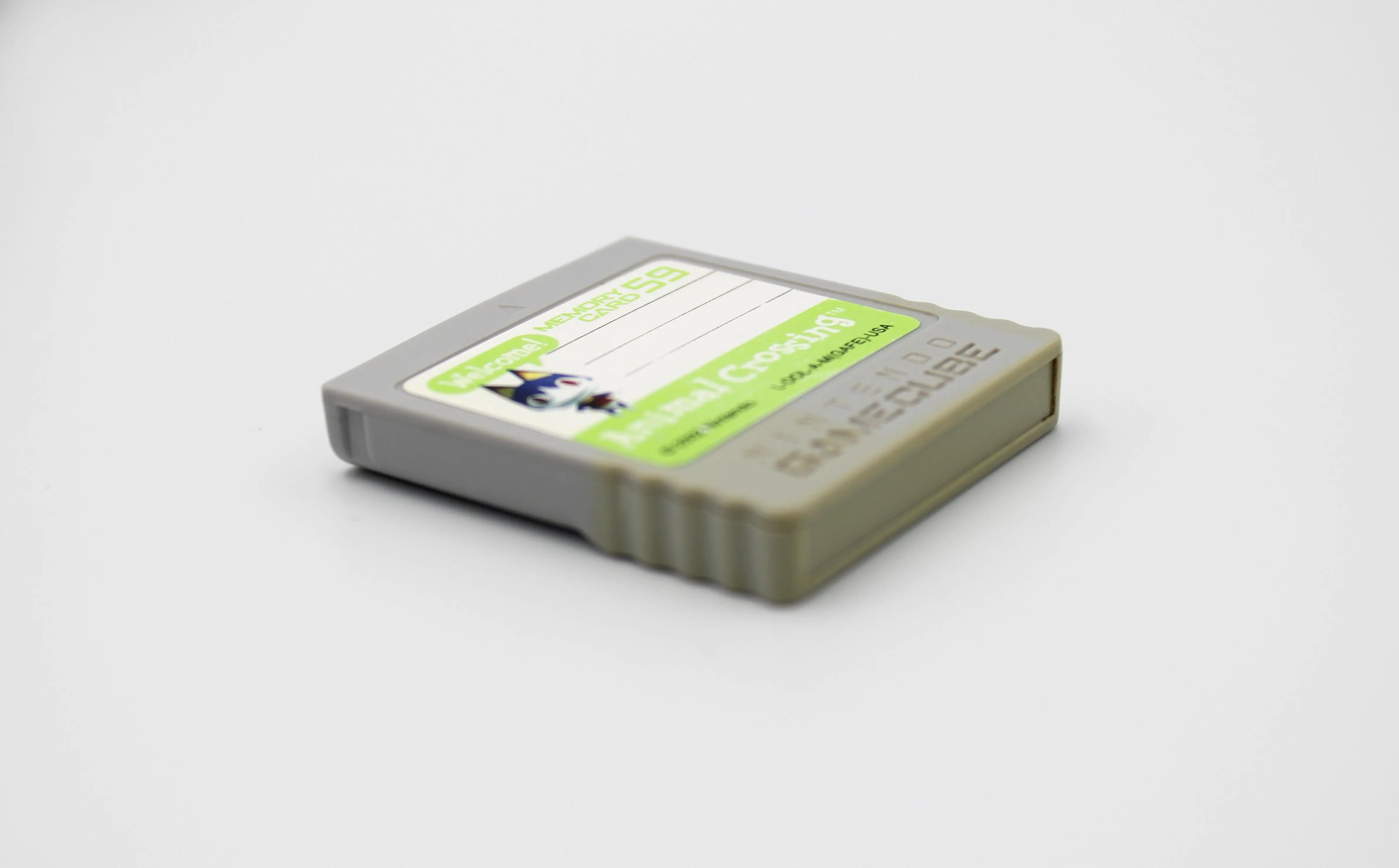 Side angle of front right of cartridge image of 2002 released NTSC-U of OEM Animal Crossing Memory Card for Nintendo GameCube – 59 Blocks (DOL-008). Displaying authentic grey Animal Crossing memory card front at a right angle with intact label and minor discoloration to the bottom of the cartridge on a clean white background.