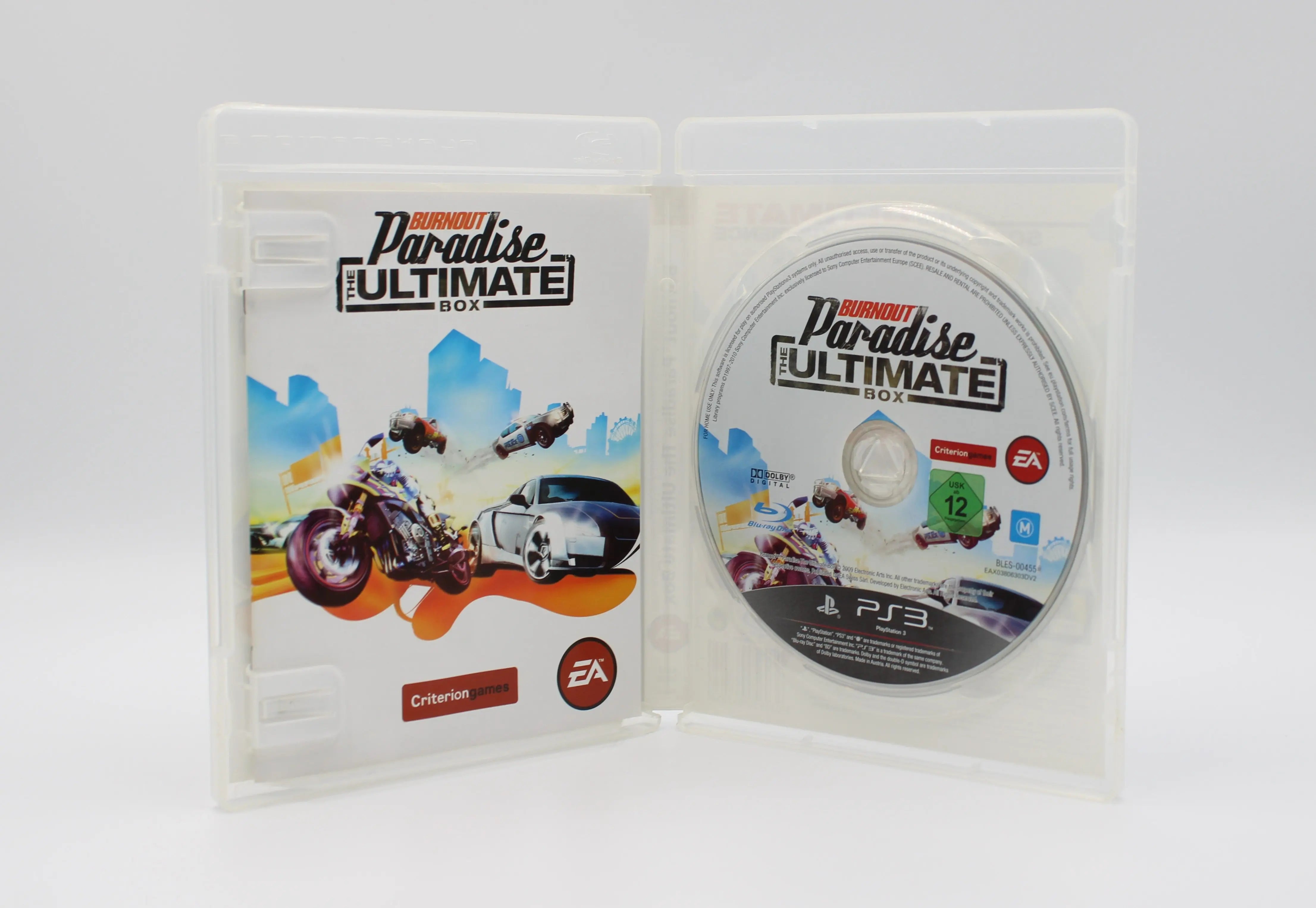 Opened case of Burnout Paradise: The Ultimate Box for PS3 PAL [Region Free], displaying Blu-ray disc and manual with any included inserts.