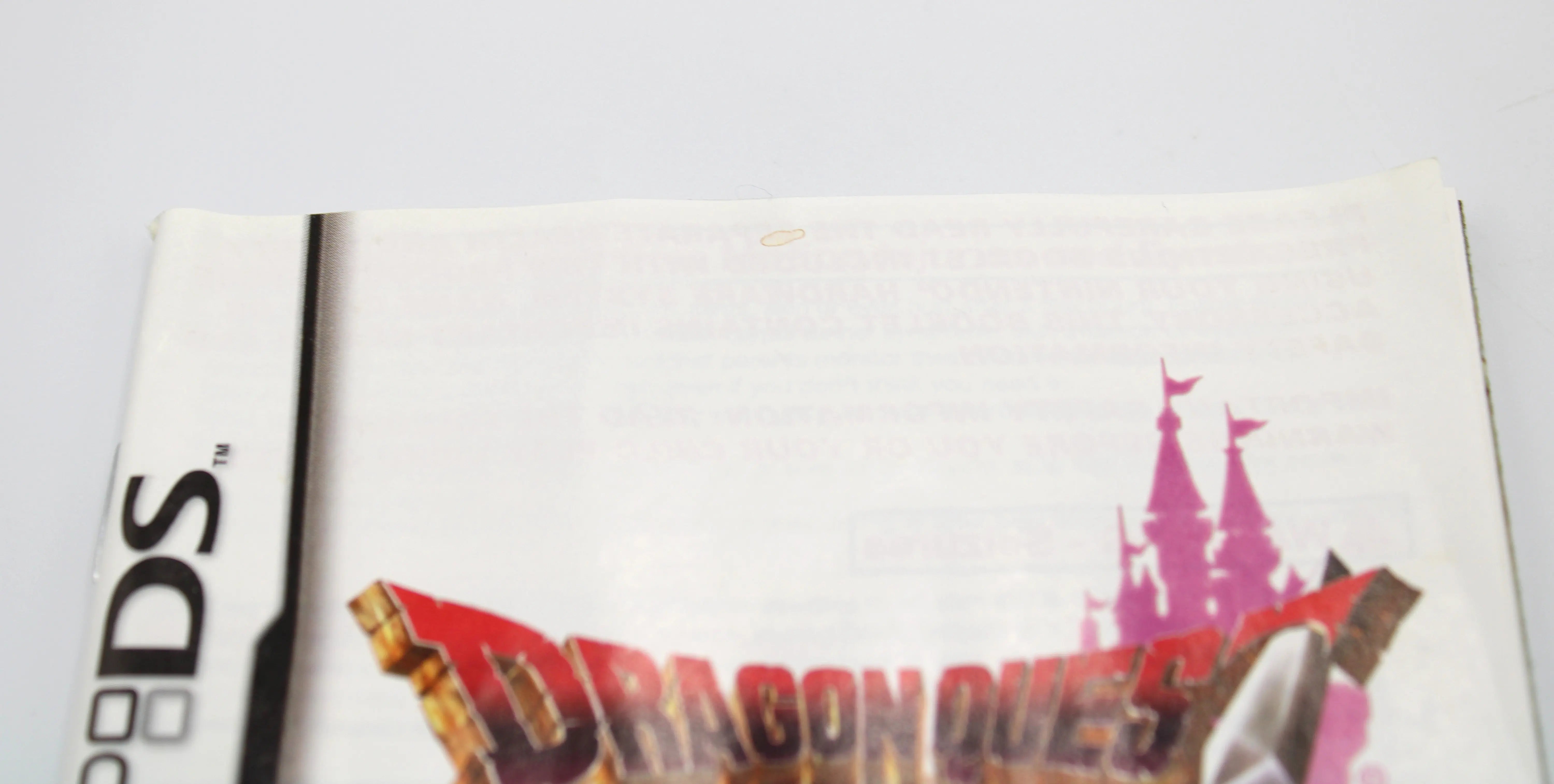 Close‑up of the combined instruction manual/health & safety booklet front for Dragon Quest IV: Chapters of the Chosen for Nintendo DS – NTSC‑U (2008), showing a very minor small brown stain near the top edge.