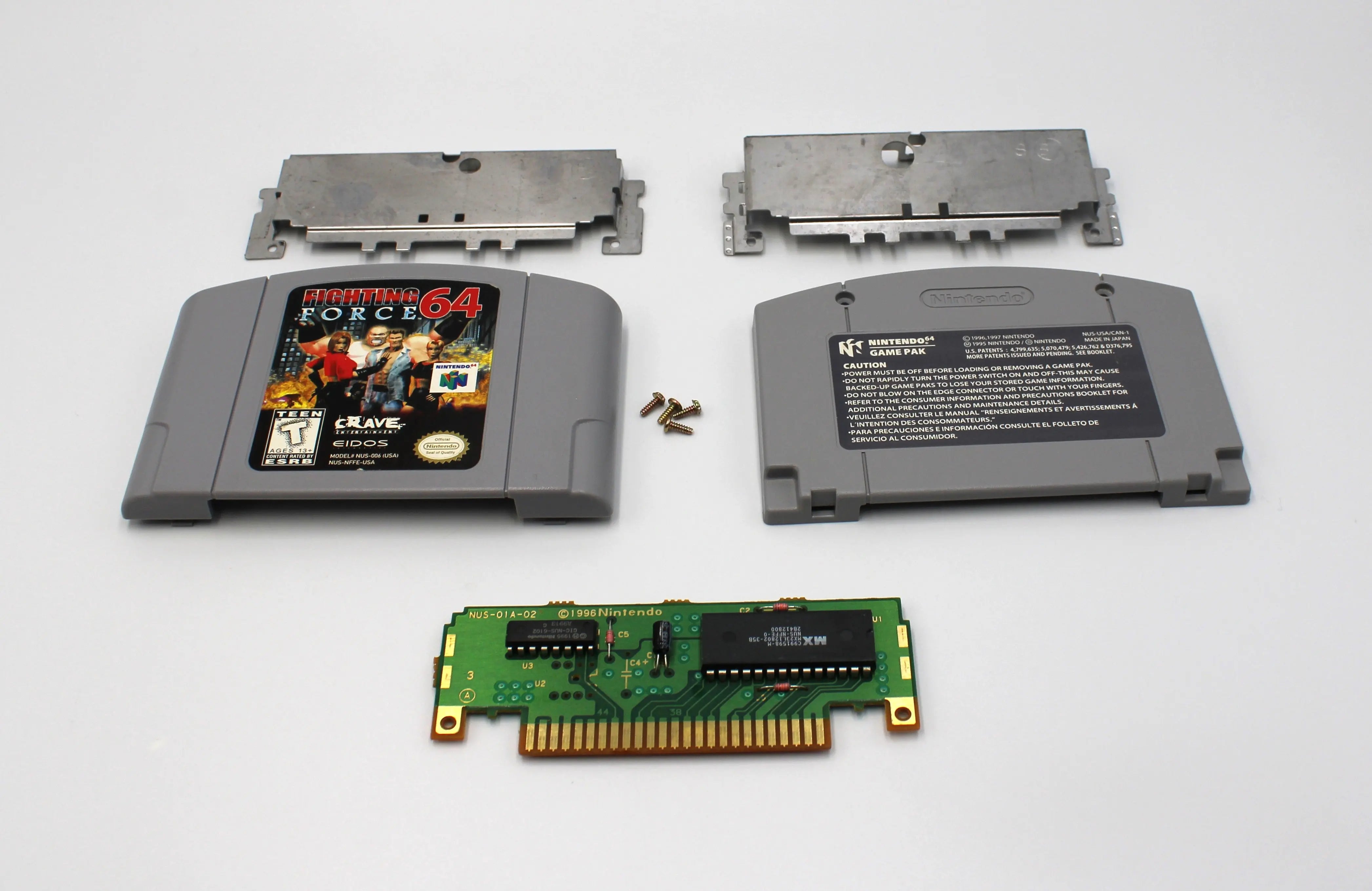 Disassembled view of NTSC-U copy of Fighting Force 64 for Nintendo 64. See picture of disassembled cartridge, screws, plates, board, and front and back shell.