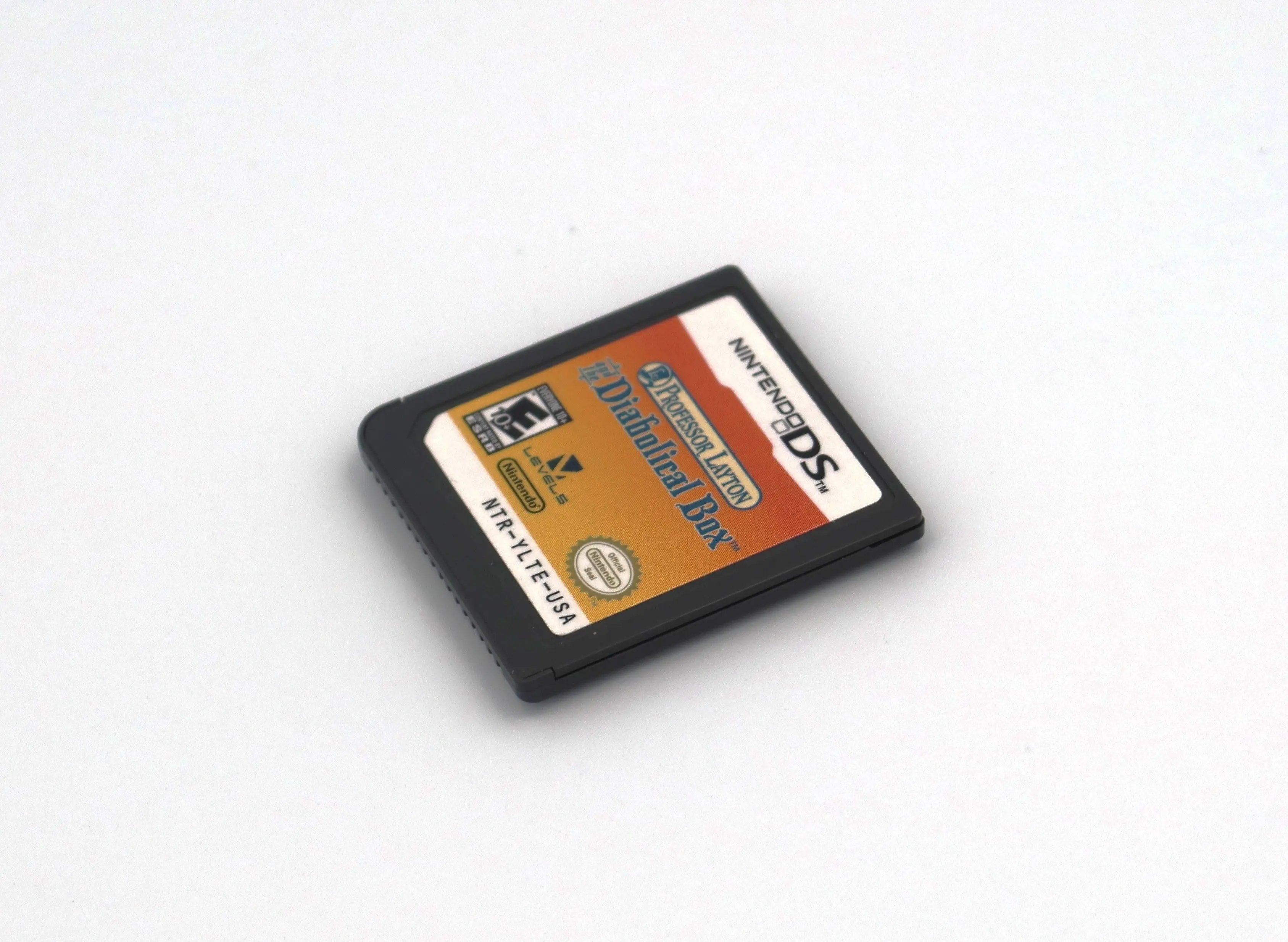 Angled front view of Professor Layton and the Diabolical Box for Nintendo DS authentic NTSC-U video game cartridge label. The label is clear and intact highlighting game title text and correct product code. All text is in correct placement and ESRB is shown for E10+ for Everyone 10 and older.