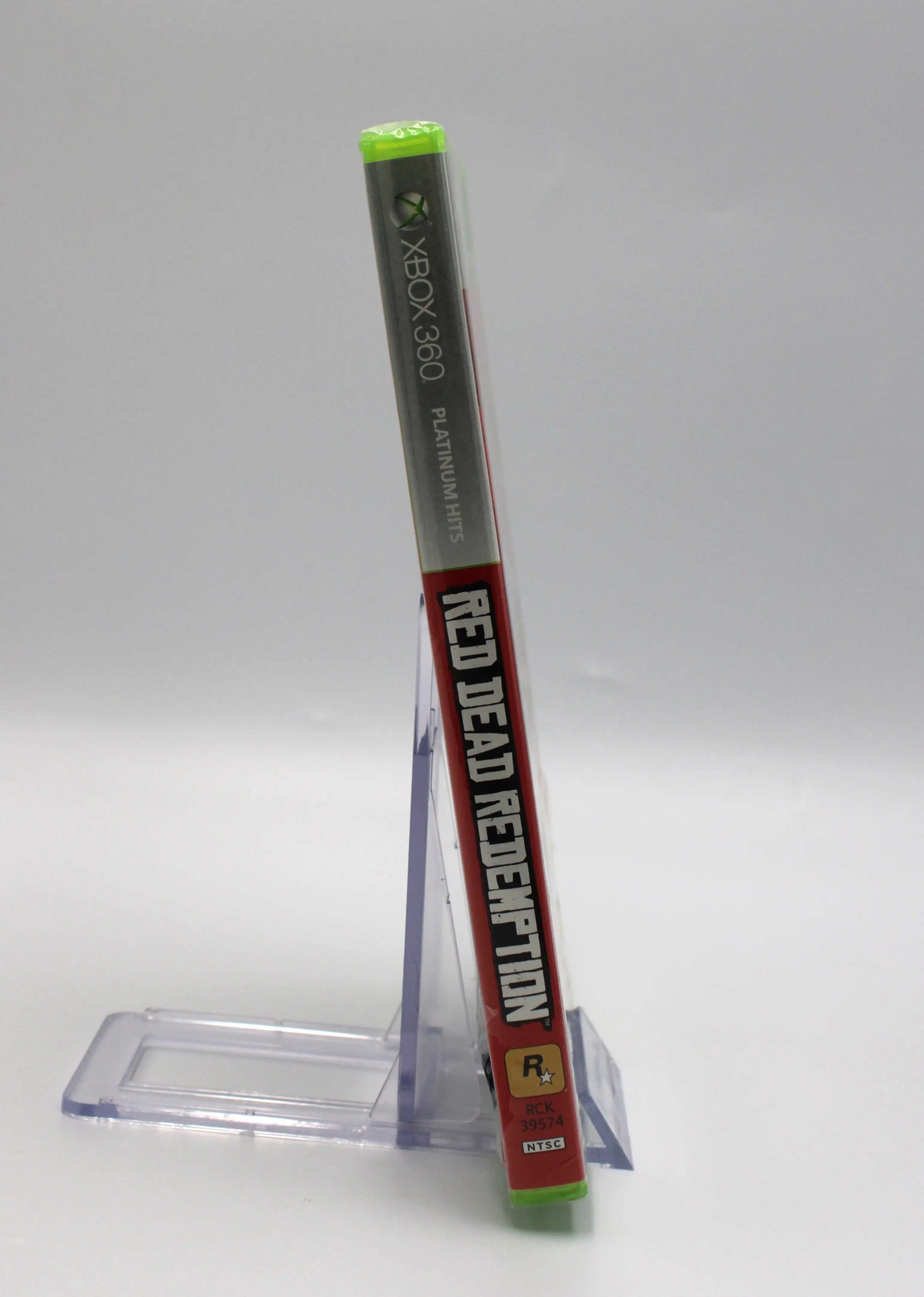 Spine view of Red Dead Redemption for Microsoft Xbox 360 NTSC-U sealed Platinum Hits game case, showing title text and sealed packaging with tear to bottom of spine.