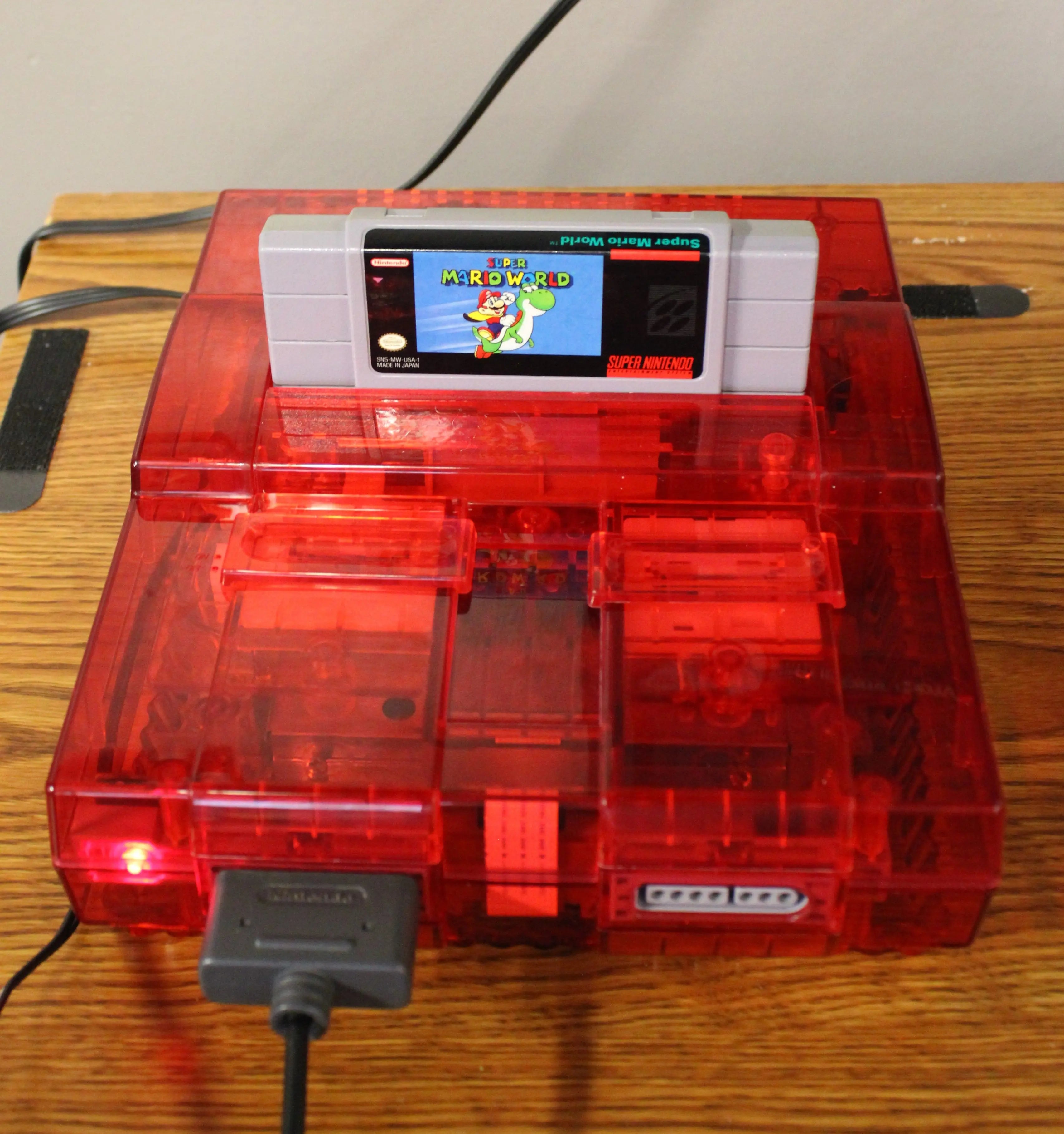 SNES powered on View: Refurbished Super Nintendo SNES with OEM controller and cables. 1991 NTSC-U console with a new red shell motherboard. Image of SNES powered up with a Mario game cartridge to ensure functionality.