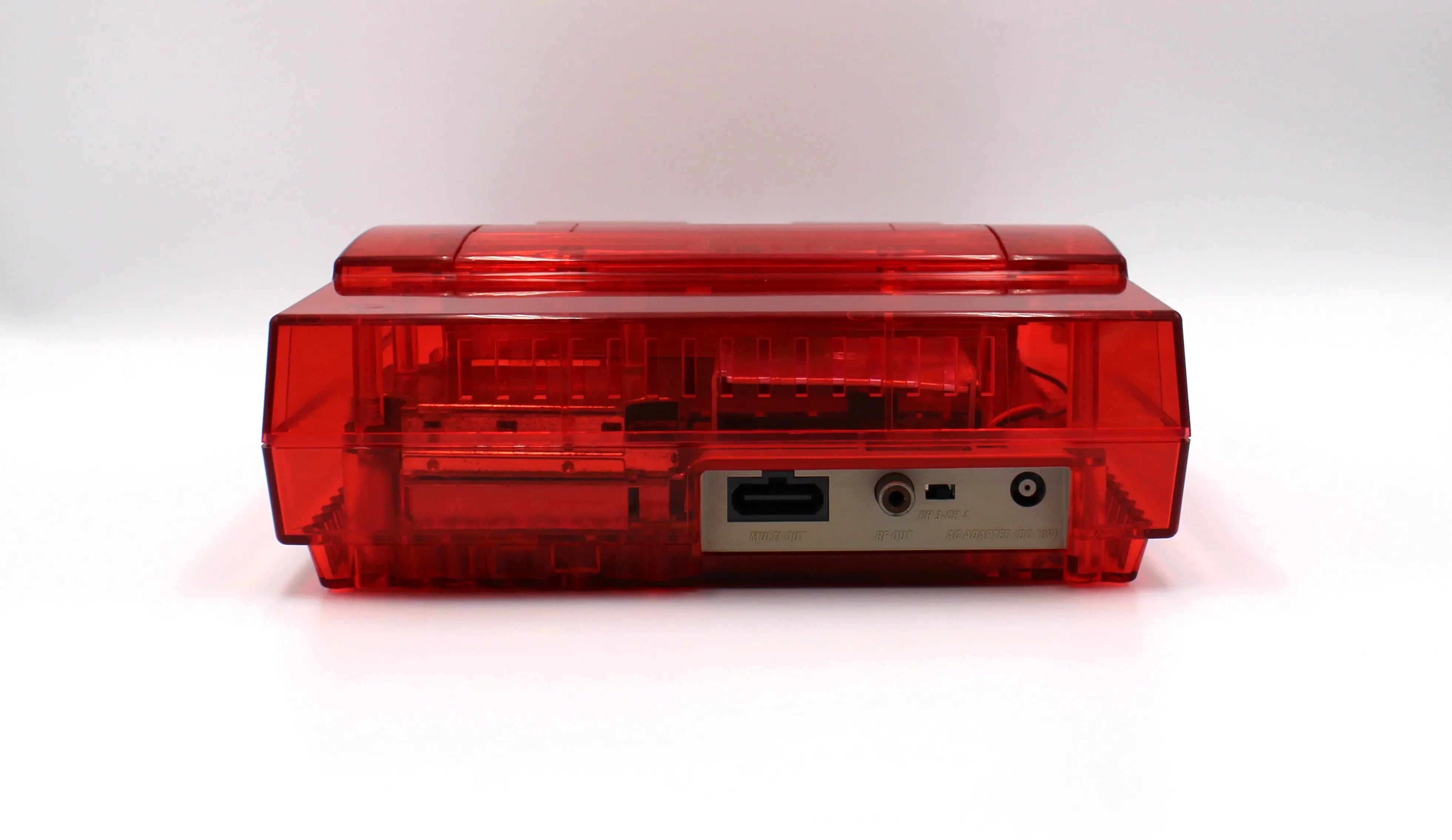 SNES Console Back View: Refurbished Super Nintendo SNES with OEM controller and cables. 1991 NTSC-U console with a new red shell motherboard. Image of back of SNES showing clean AV port, RF, and power supply plug in, and new red shell