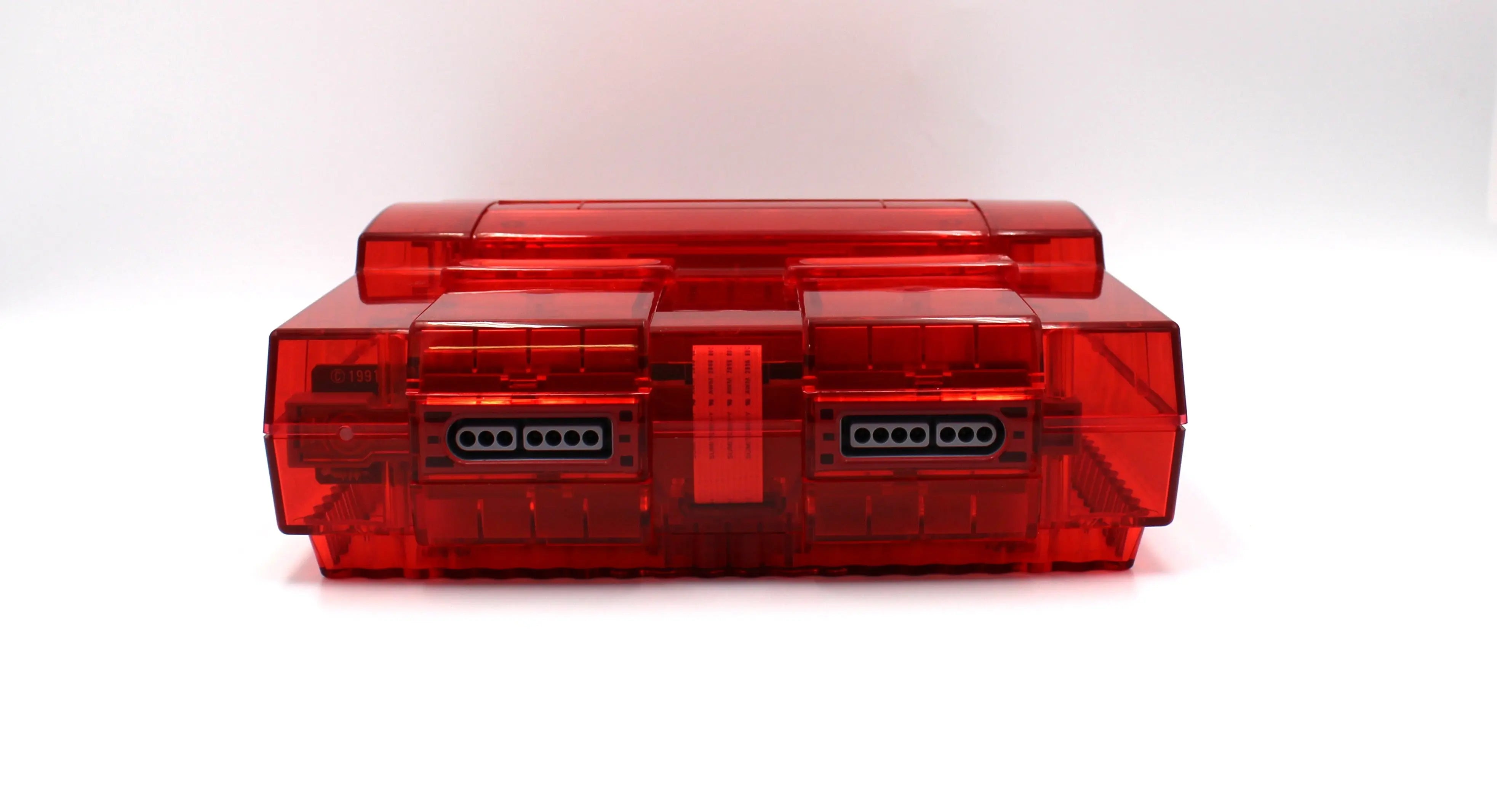 SNES Console Front View: Refurbished Super Nintendo SNES with OEM controller and cables. 1991 NTSC-U console with a new red shell motherboard. Image of front of SNES showing clean controller ports and new red shell.