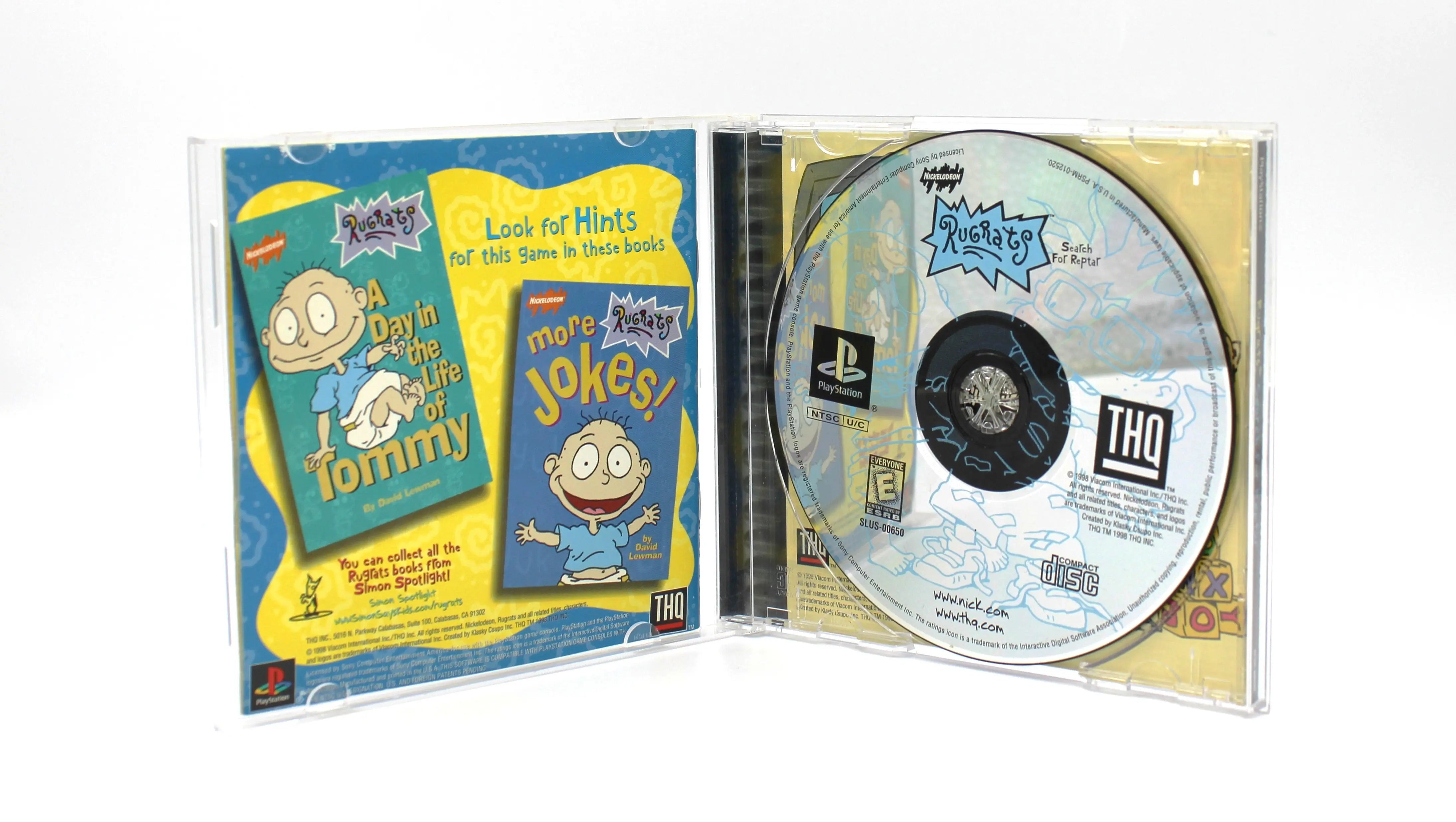 Open case: Interior view of Rugrats: Search for Reptar for Sony PlayStation 1 (PS1) – CIB with Registration Card (1998) NTSC-U, black label edition, opened case showing the disc in the tray and the manual in the sleeve.