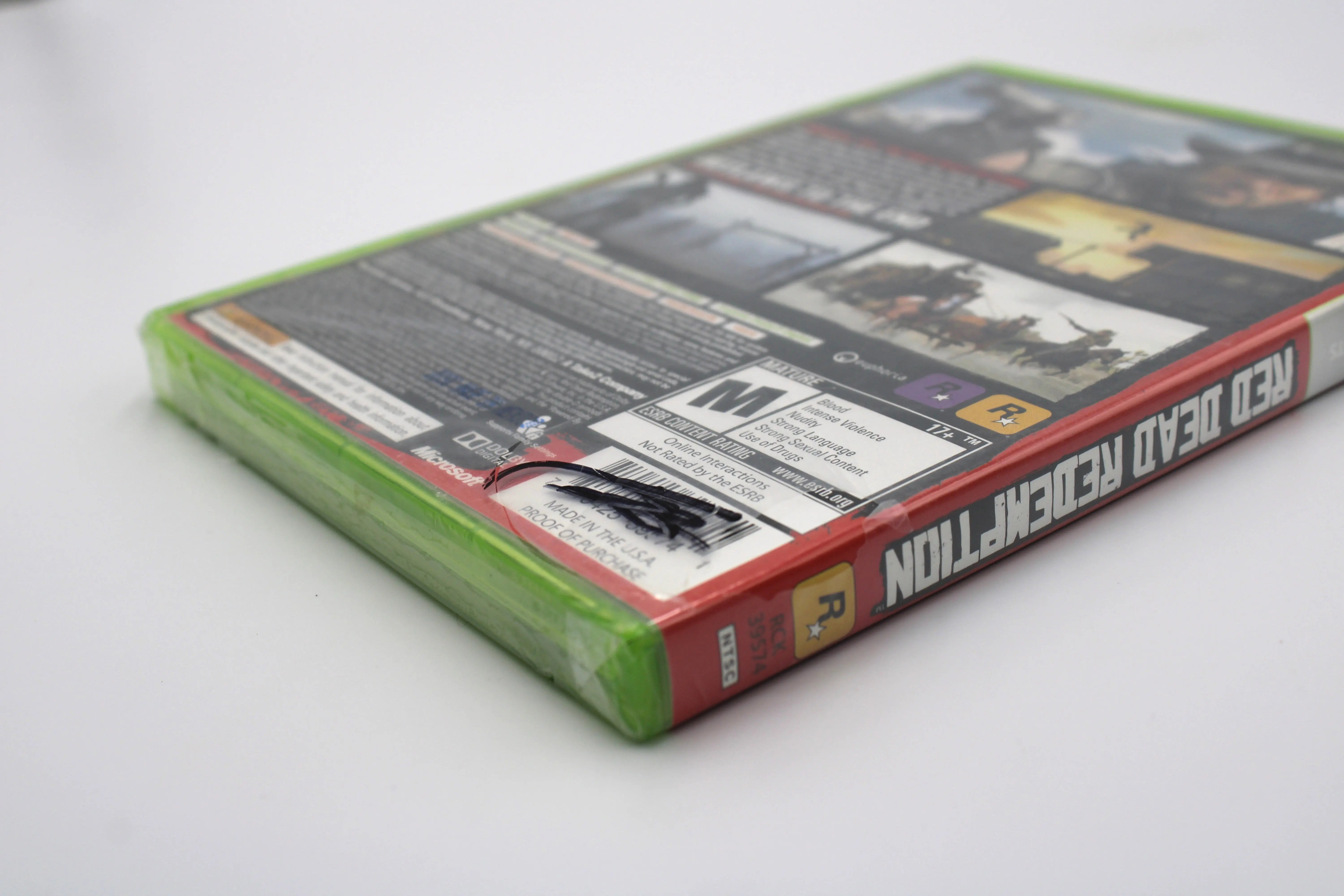 Back Corner view of Red Dead Redemption Platinum Hits for Microsoft Xbox 360 NTSC-U sealed game case, showing sharpie on seal located over UPC barcode to back of game case.