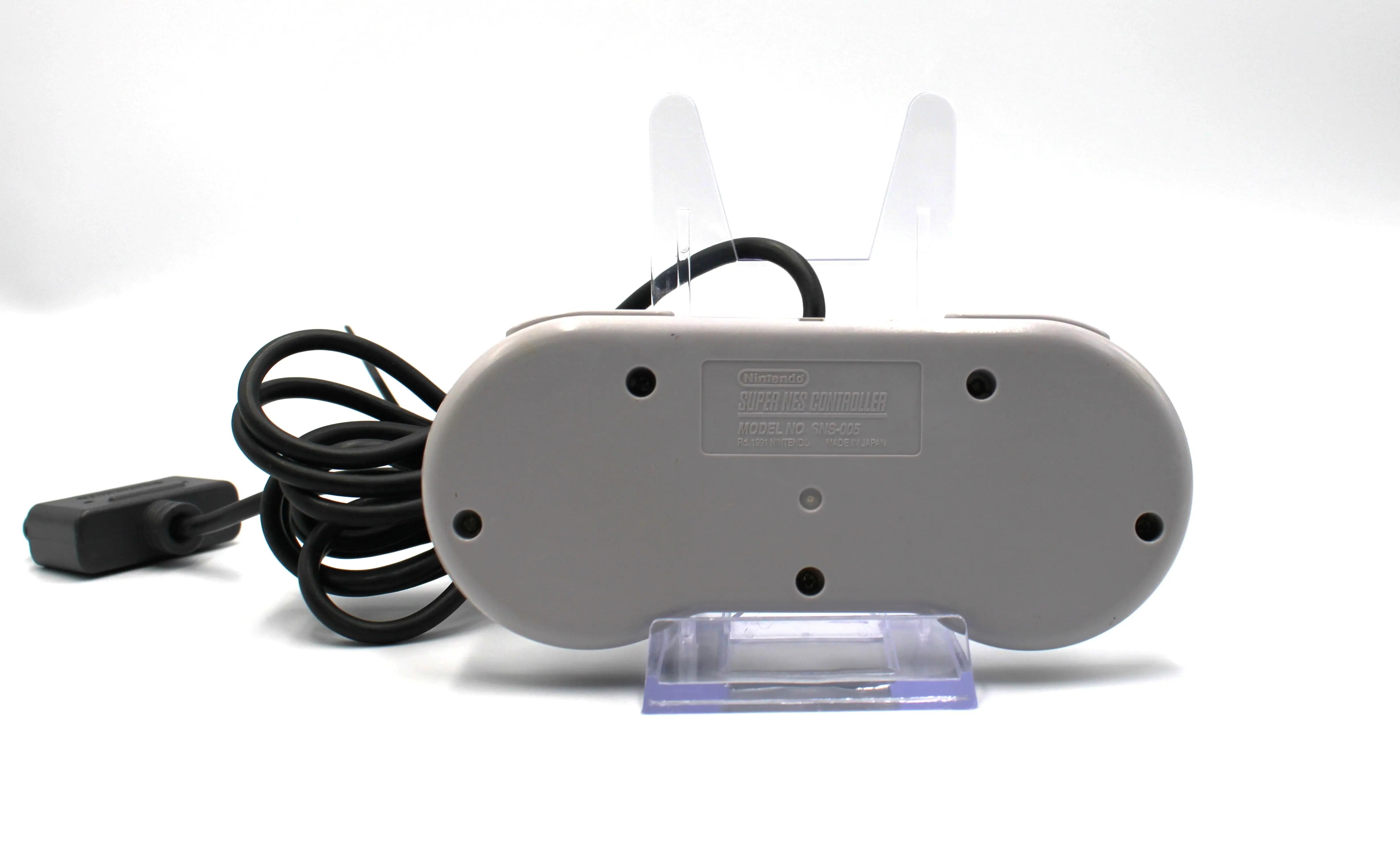 OEM SNES Controller Back View: Refurbished Super Nintendo SNES with OEM controller and cables. 1991 NTSC-U console with a new translucent red shell. Image of Back of refurbished SNES controller with Super NES text, clean condition with some yellowing from age against a white background.