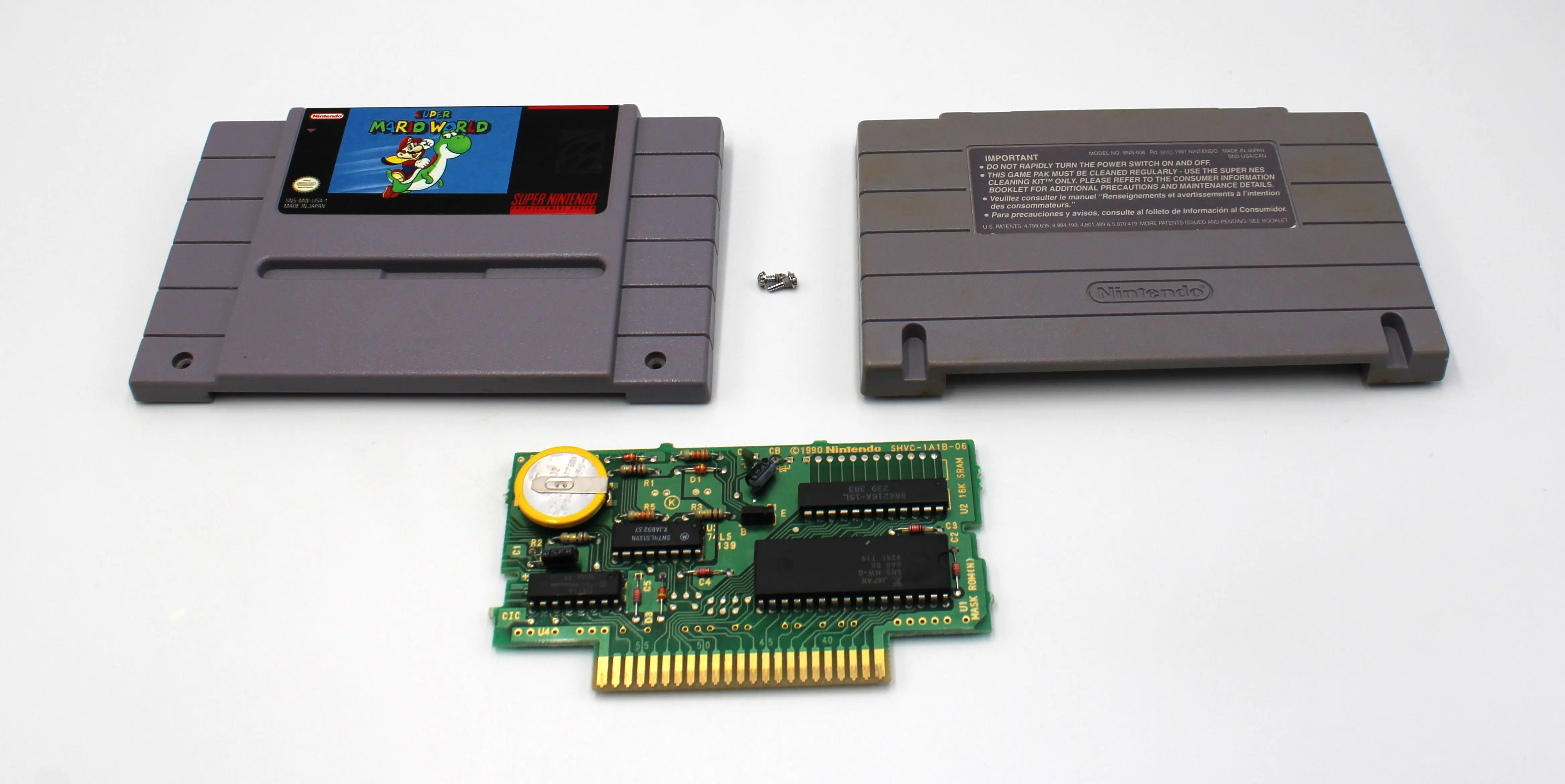 Disassembled view of authentic NTSC-U copy of Super Mario World for Super Nintendo SNES. 1991. See picture of front game label cartridge, back label cartridge, screws, game board with new CR2031 3V battery.