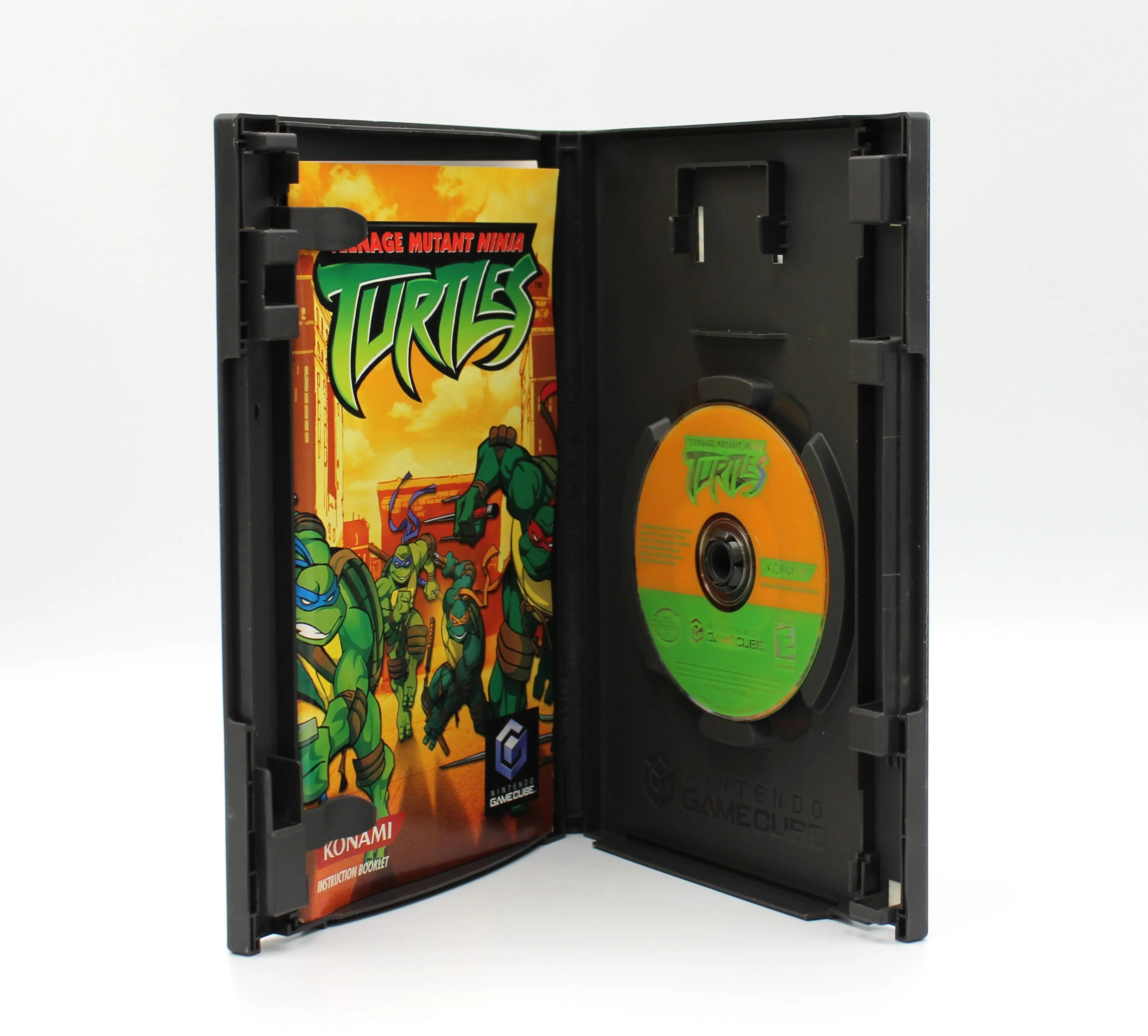 Interior of Teenage Mutant Ninja Turtles for Nintendo GameCube – CIB with Inserts (2003) showing the instruction manual and inserts in the left panel and the game disc secured in the right tray, on a white background.