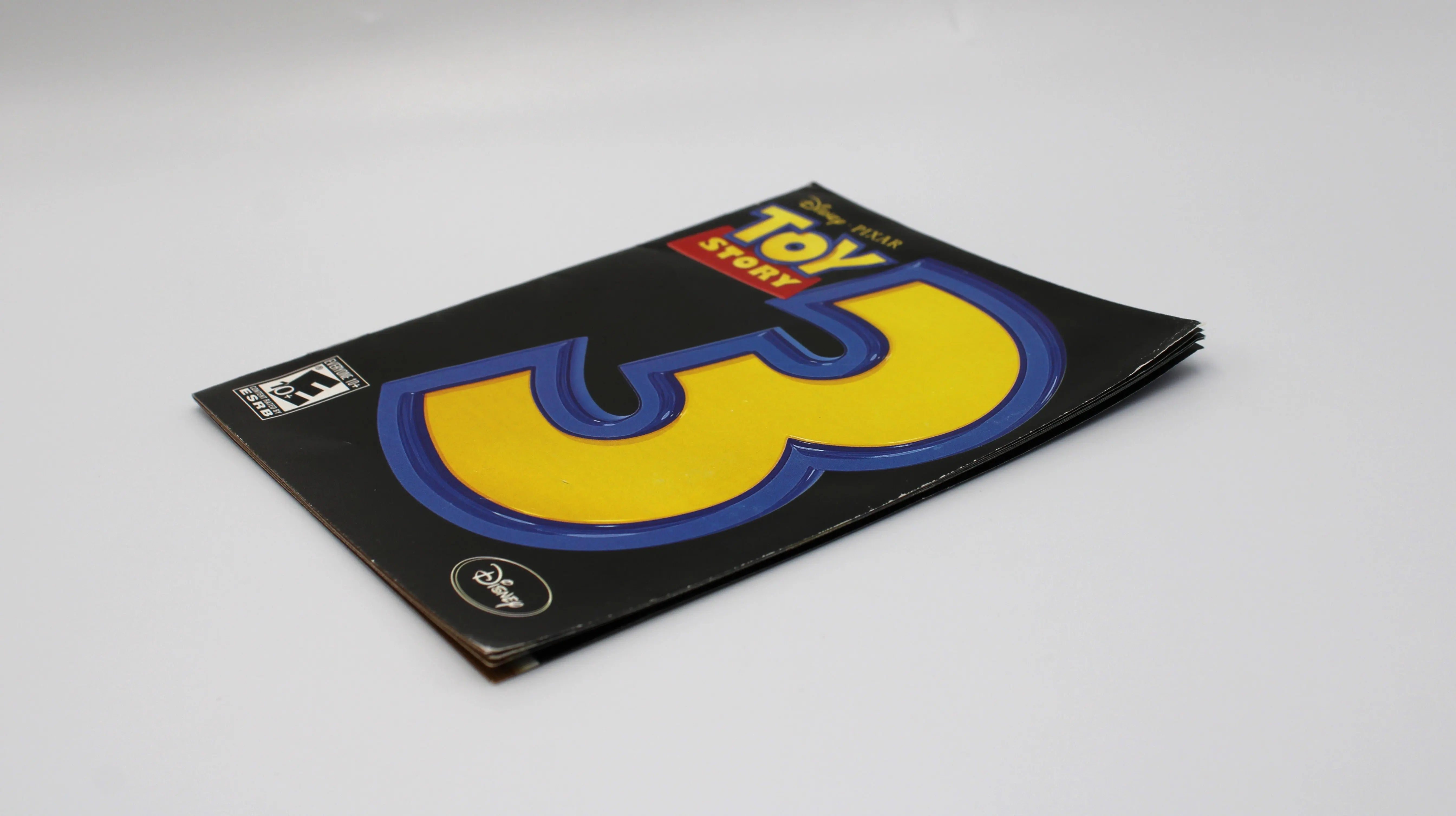 Manual Insert angle: Game insert laying flat at an angle of Toy Story 3: The Video Game for Sony PlayStation PS3 NTSC‑U, showing the intact manual’s cover artwork and text viewed diagonally against a white surface with some minor cosmetic wear.