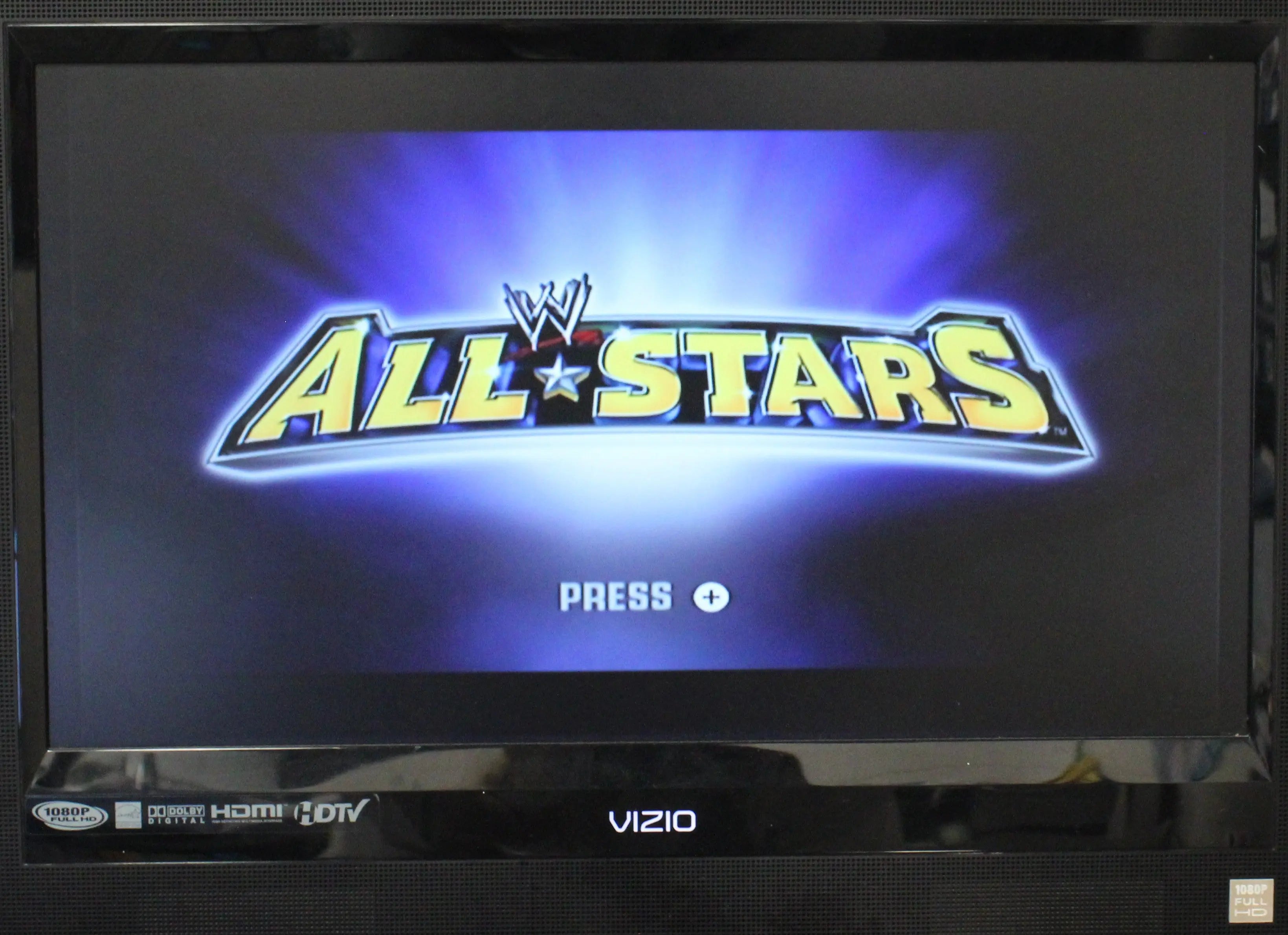 Gameplay main menu screen of WWE All Stars for Nintendo Wii – CIB with Manual (2011) NTSC-U, showing the yellow “All Stars” logo on a purple radial background with a “Press +” start-button prompt below.
