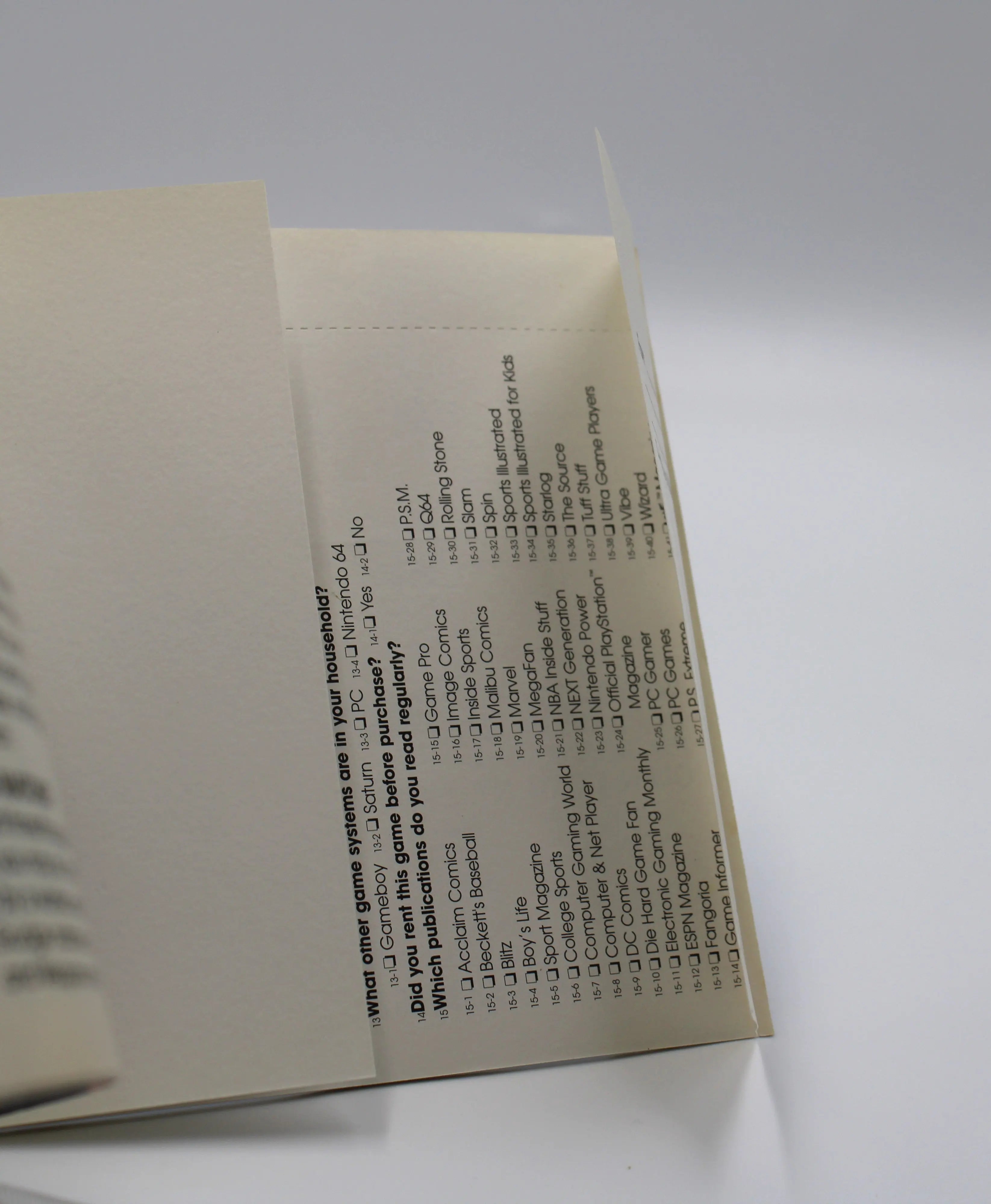 View o side of registration card attached to the booklet of the black label variant of Sony's game title WWF War Zone for the Sony PlayStation 1 console. Clearly shows the Acclaim warranty registration card is unused and intact. Displaying unchecked boxes to mark for new video game options at the 1998 time era.